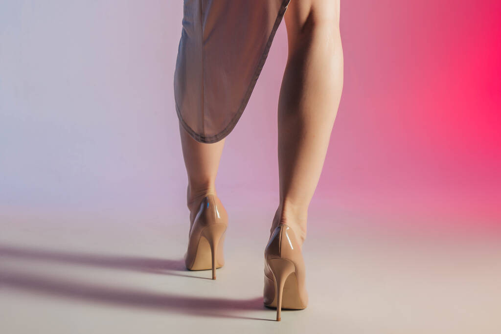 Testrészek, gyönyörű lábak. Gyönyörű barna egy rövid bézs ruha egy gradiens színű háttér. Pózok, hely szöveg, ábra, vékony lány - Fotó, kép