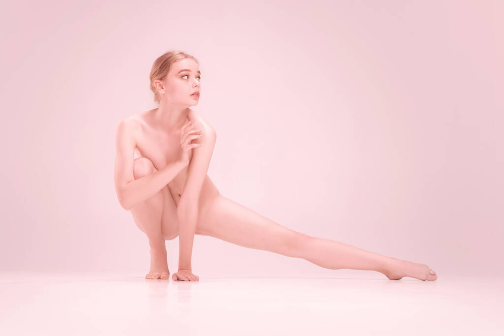 Elegante frágil joven desnuda hermosa chica posando aislado sobre fondo de estudio rosa. Concepto de belleza, pureza, ternura y gracia. - Foto, Imagen