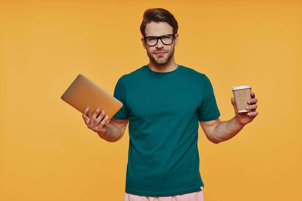Schöner junger Mann in Freizeitkleidung mit digitalem Tablet und Tasse - Foto, Bild