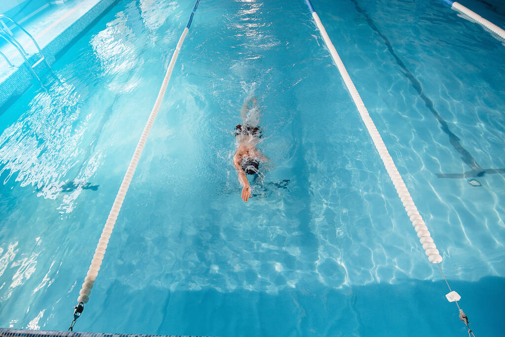 Ένας νεαρός αθλητής προπονείται και προετοιμάζεται για κολυμβητικούς αγώνες στην πισίνα. Υγιής τρόπος ζωής. - Φωτογραφία, εικόνα