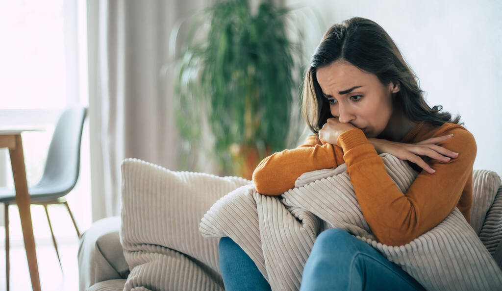 Сумна жінка в глибокій депресії сидить на дивані і плаче і думає про погану річ
 - Фото, зображення