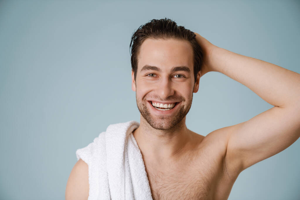 gelukkig brunette bebaarde shirtloze man met handdoek over blauwe muur - Foto, afbeelding