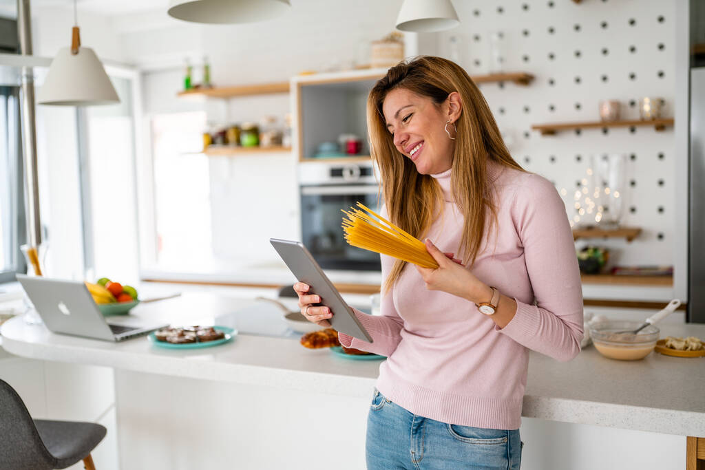 Ritratto di bella donna felice con pasta in cucina, che si prepara a cucinare - Foto, immagini
