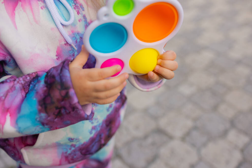 Mettilo in mano a una ragazza. Giocattolo colorato antistress per bambini fidget. - Foto, immagini