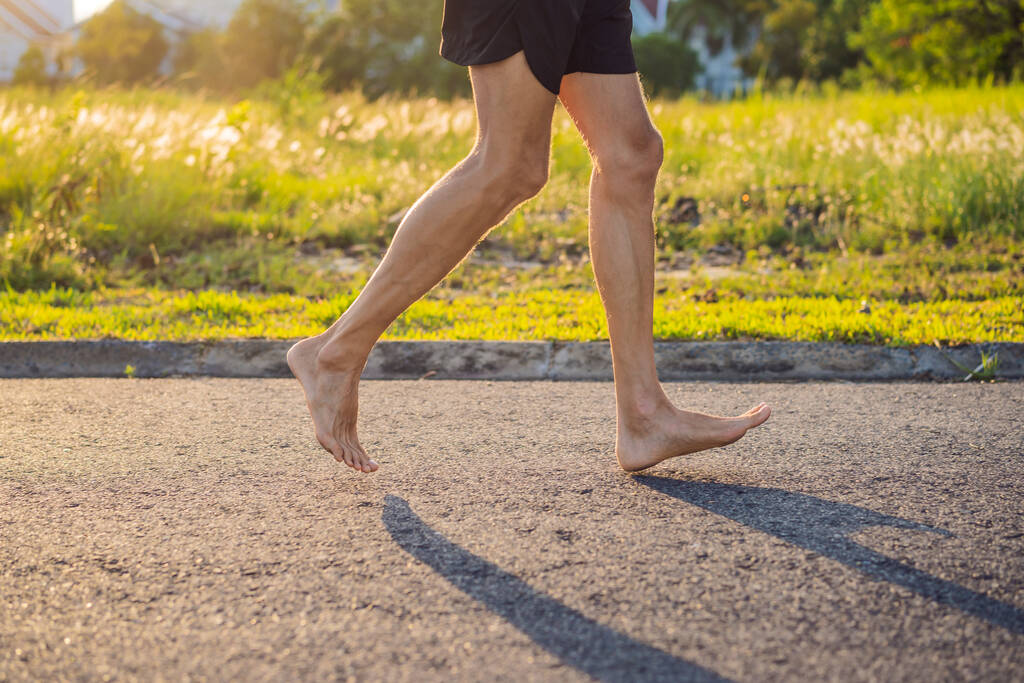 Mies juoksija on mukana lenkkeilemässä asfaltilla ilman kenkiä, ilman lenkkareita, terveydelle. - Valokuva, kuva