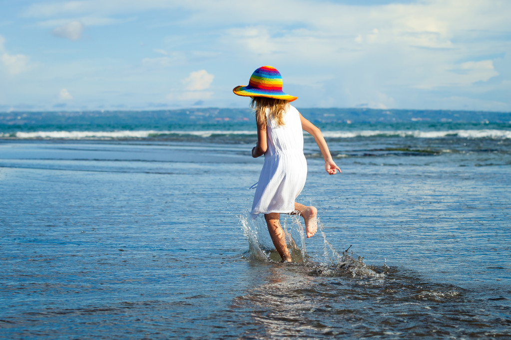 Onnellinen pieni tyttö kävelee rannalla päivällä
 - Valokuva, kuva