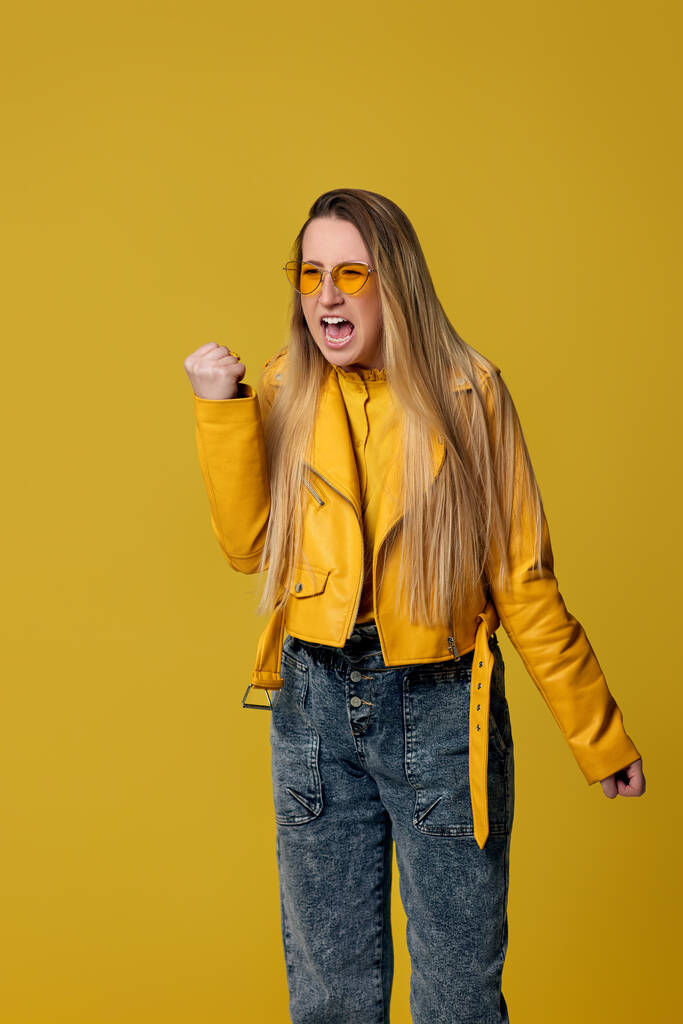 θυμωμένη γυναίκα με γυαλιά ηλίου ουρλιάζοντας σε κίτρινο φόντο. - Φωτογραφία, εικόνα