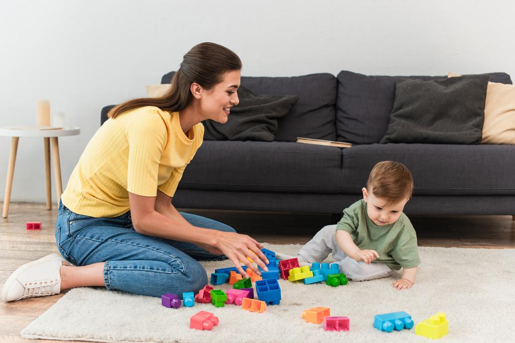 Smiling mother playing building blocks in living room  - Photo, Image