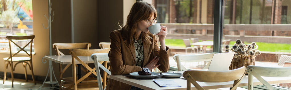 Jonge stijlvolle vrouw die koffie drinkt in de buurt van het dessert in cafe, spandoek  - Foto, afbeelding