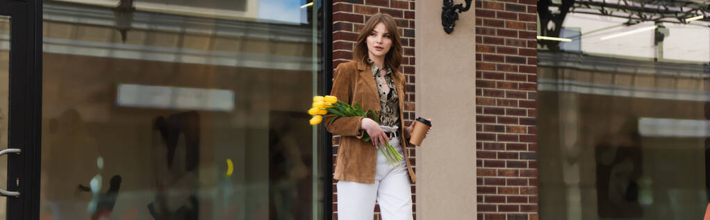 stylowa kobieta z papierowym kubkiem trzymając tulipany i spacery na zewnątrz, baner - Zdjęcie, obraz