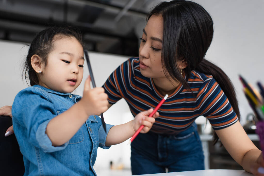 Asiática madre mirando a hija con lápices de color  - Foto, Imagen