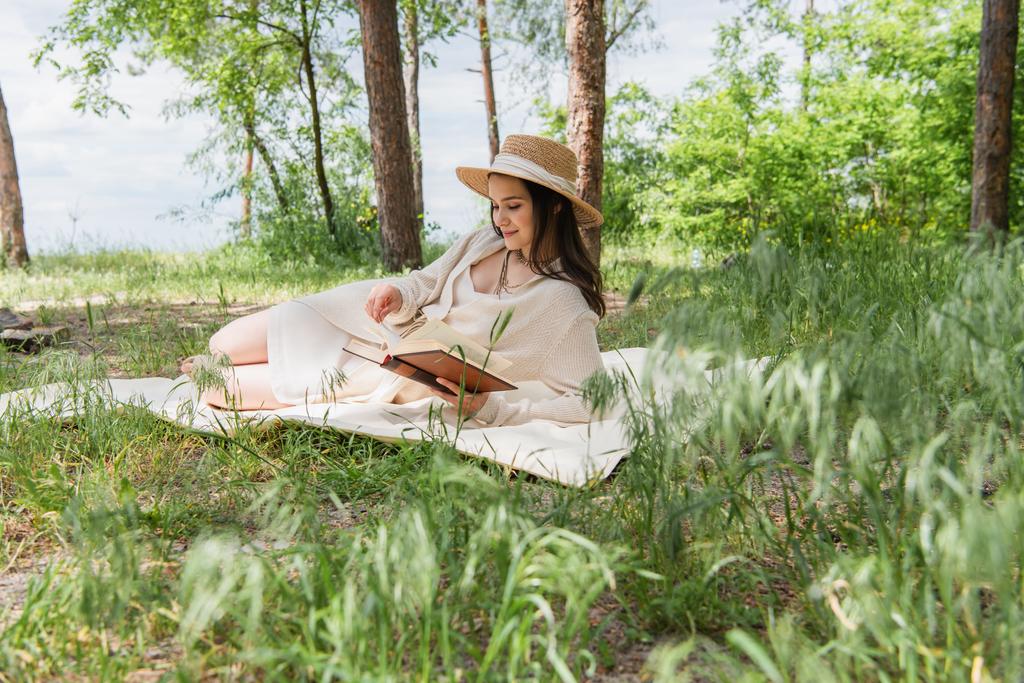 jovem alegre em chapéu de palha leitura livro na floresta  - Foto, Imagem