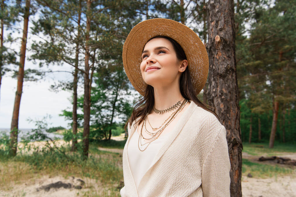 alegre joven mujer en sombrero de sol sonriendo en el bosque - Foto, imagen