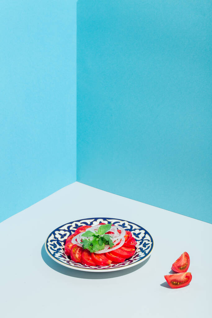 トマトを玉ねぎとバジルでカットしたサラダ東洋のブループレート現代的ミニマリズム - 写真・画像