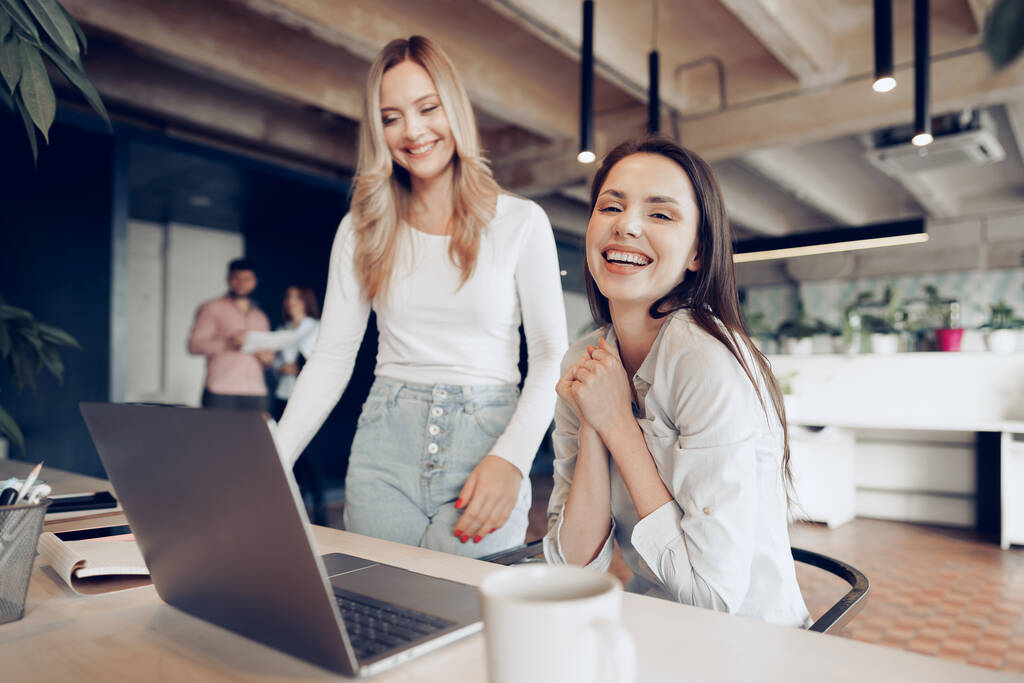 Две молодые счастливые предпринимательницы празднуют успех проекта в офисе - Фото, изображение