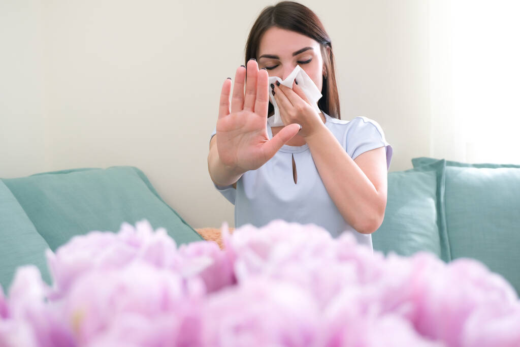 Młoda kobieta kicha z powodu alergii na kwiaty. Alergia pyłkowa - Zdjęcie, obraz