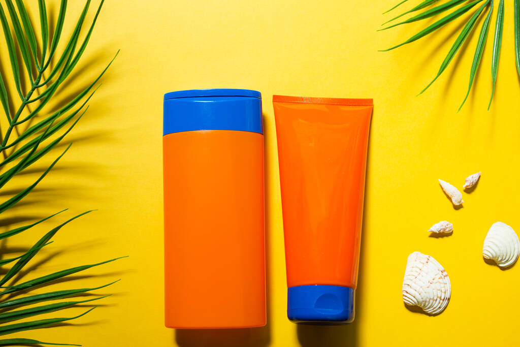 Dos tubos con protectores solares simulados sobre un fondo amarillo de verano. Protección UV de la piel con filtro SPF, champú para el cuidado del cabello y acondicionador. Un bronceado seguro en la playa. Piso laico - resort en el mar. - Foto, Imagen