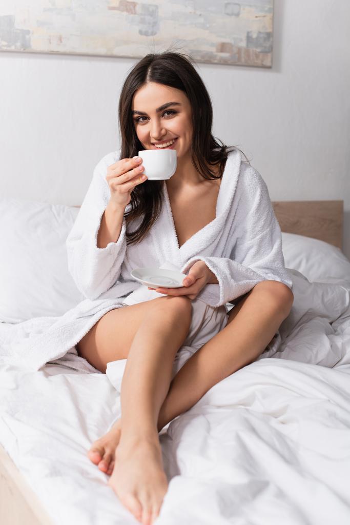 onnellinen nuori nainen tilalla lautanen ja kahvin juominen - Valokuva, kuva