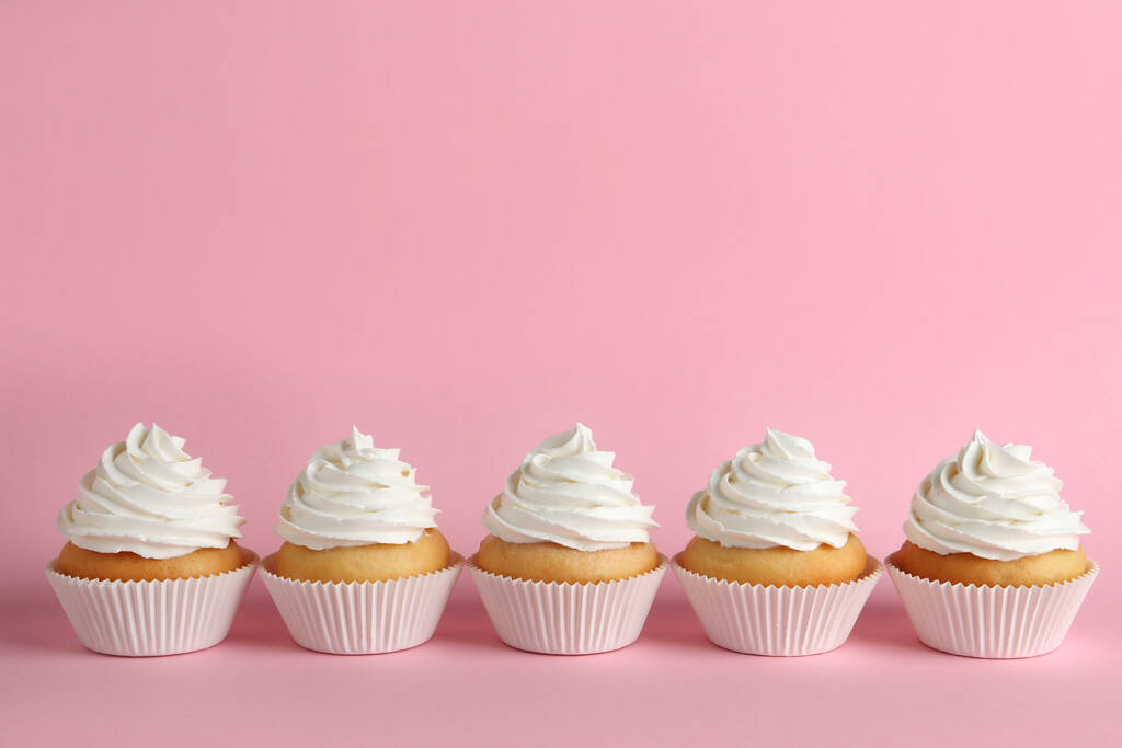 Deliciosos cupcakes con crema blanca sobre fondo rosa. Espacio para texto - Foto, Imagen