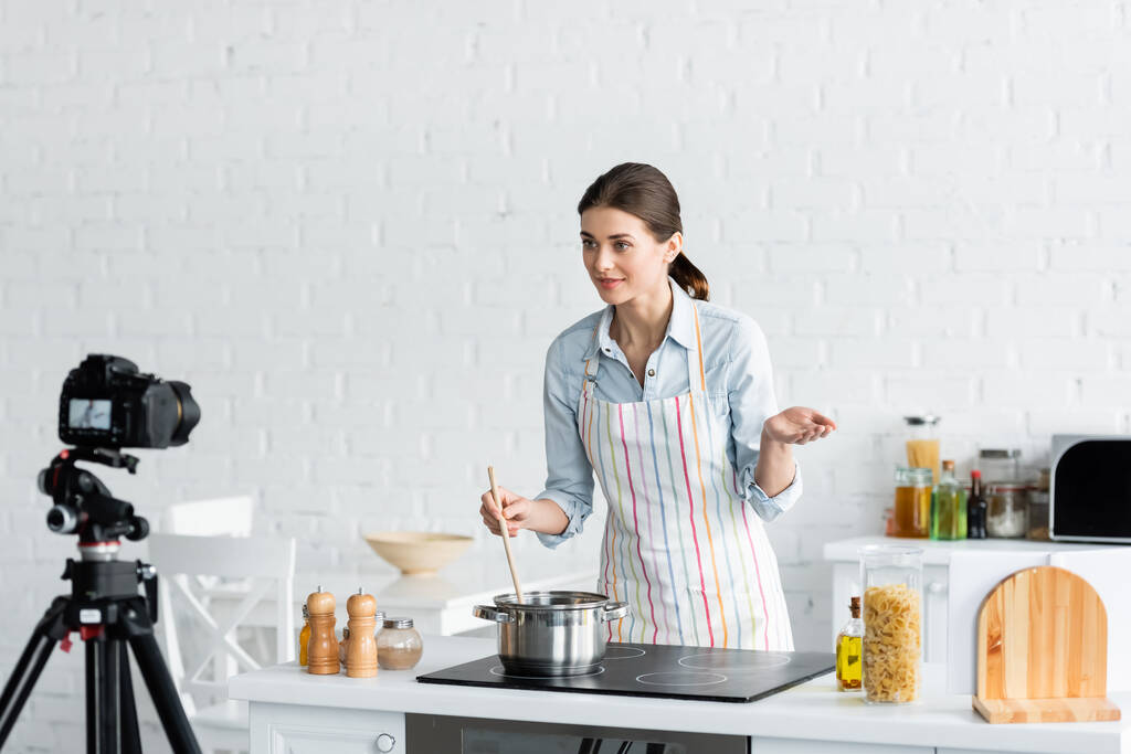 молодий кулінарний блогер розмовляє біля цифрової камери під час приготування їжі на кухні
 - Фото, зображення