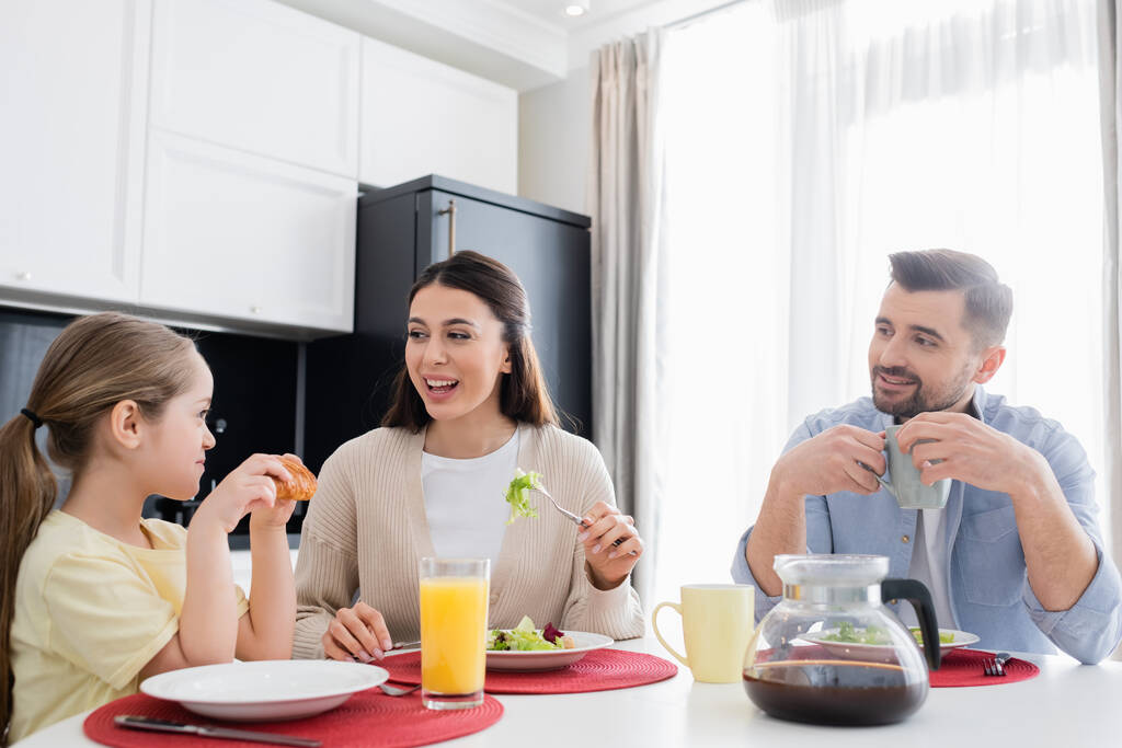 iloinen nainen syö kasvissalaattia aamiaiseksi lähellä vaimoa ja miestä  - Valokuva, kuva