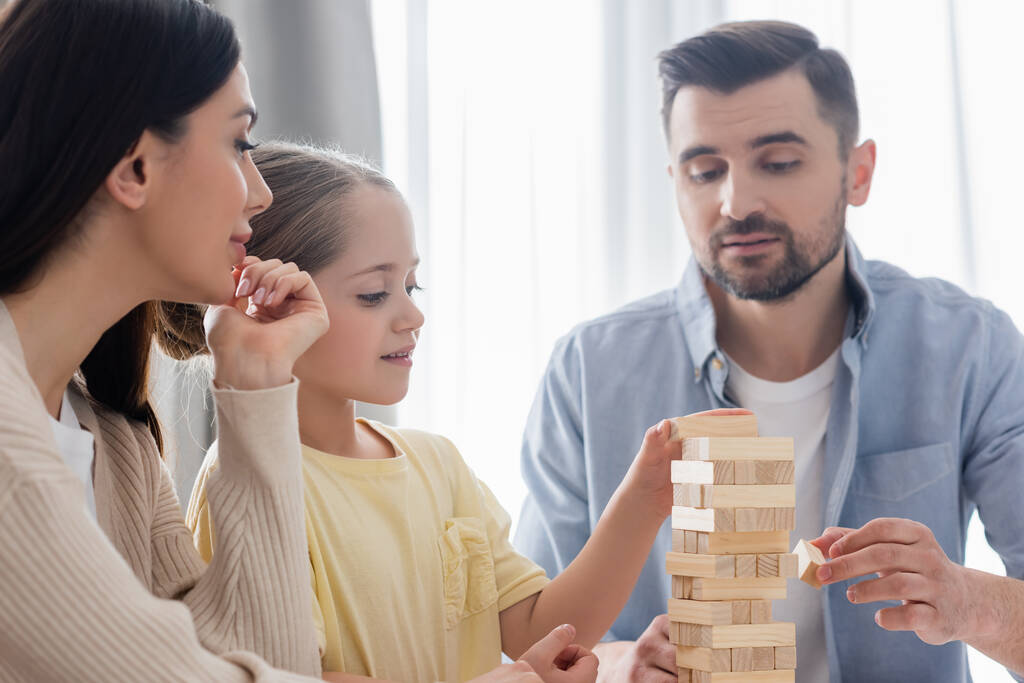 couple with daughter playing wood tower game at home  - Photo, Image