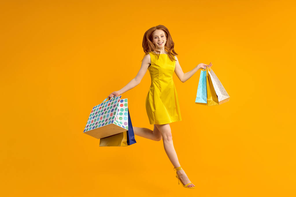 joven pelirroja suerte mujer saltar divertirse con paquetes de compras en las manos - Foto, imagen