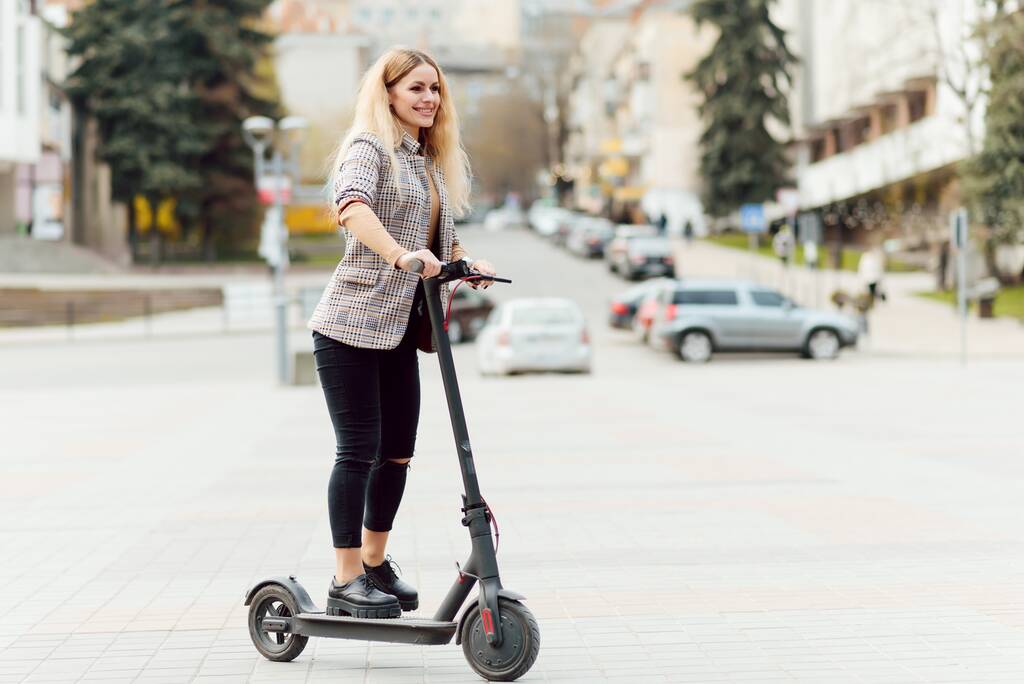 Meisje in elektrische scooter rijden in het oude centrum - Foto, afbeelding