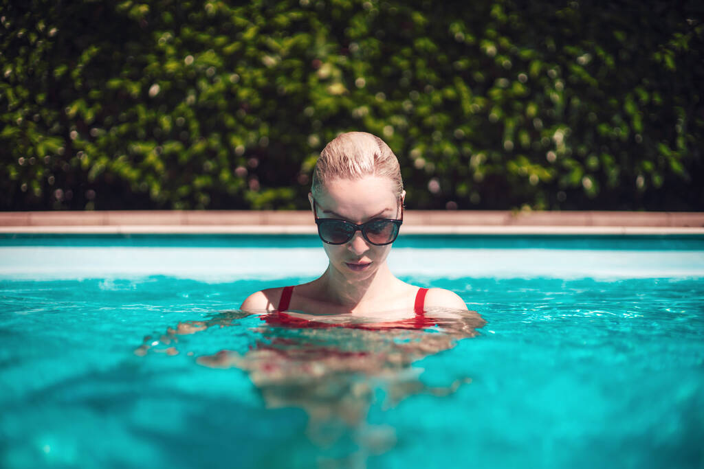 Jong mooi sexy meisje genieten van zwemmen in het prive zwembad en ontspannen in de zon. Zomertijd. - Foto, afbeelding