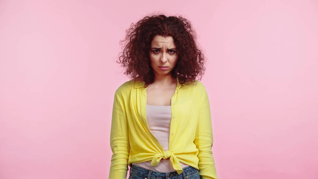 offended and curly woman standing isolated on pink  - Photo, Image