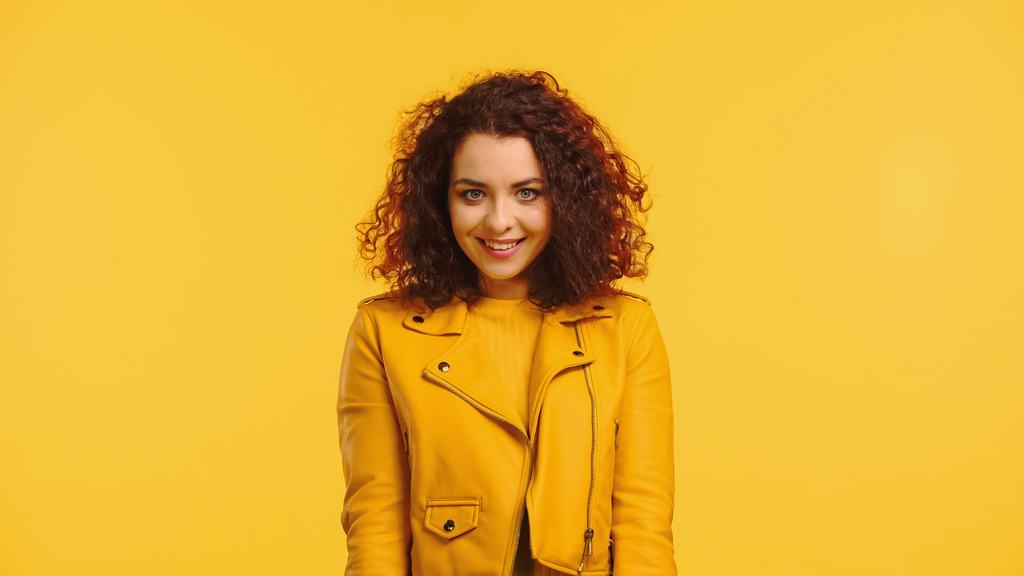 happy young woman in jacket isolated on yellow - Photo, Image