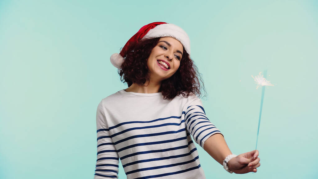 Noel Baba şapkalı neşeli genç kadın elinde maytap tutuyordu. - Fotoğraf, Görsel