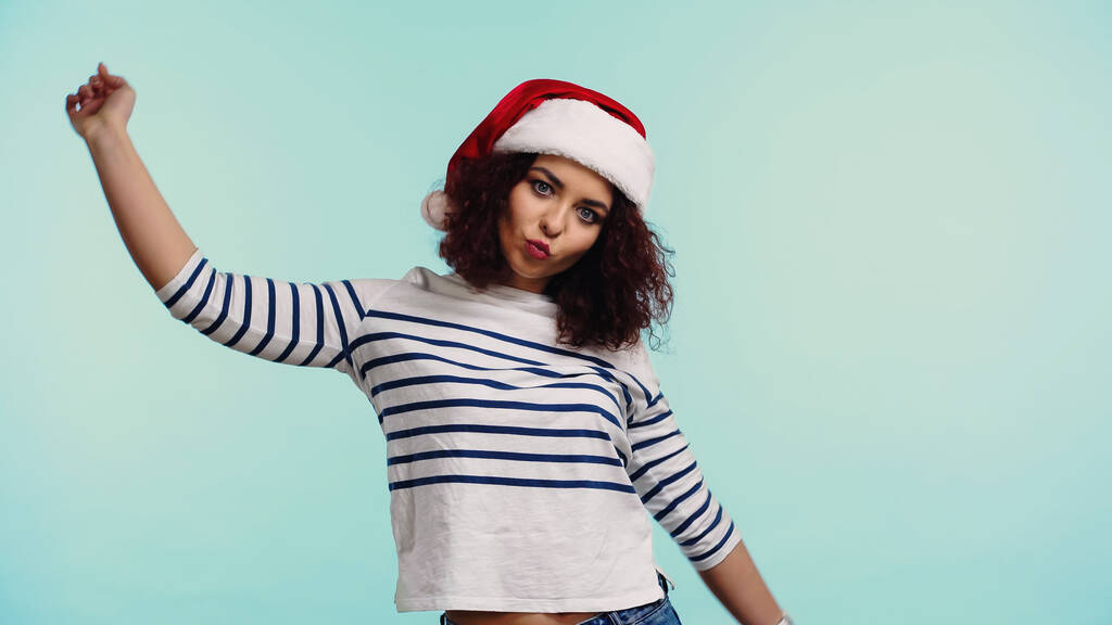 young woman in santa hat pouting lips isolated on blue - Photo, Image
