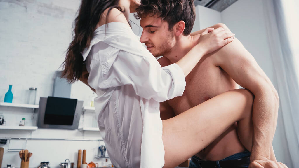 homme torse nu embrassant femme passionnée avec des jambes nues dans la cuisine - Photo, image