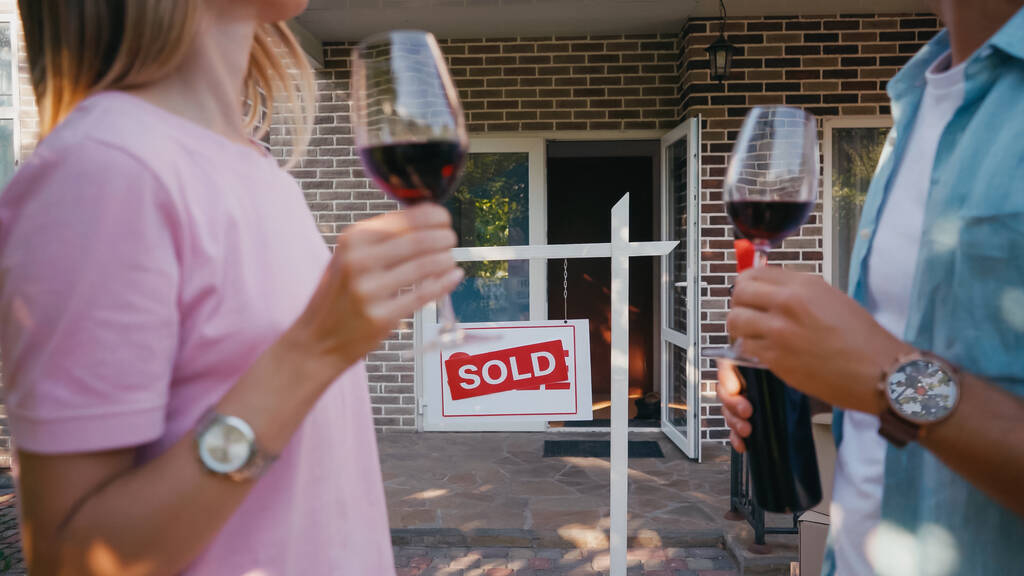 maison et pension avec lettrage vendu près du couple flou avec des verres de vin rouge  - Photo, image