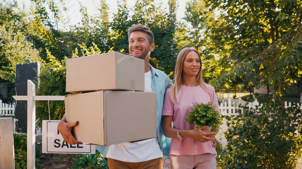 alegre marido e mulher andando com caixas e planta verde, conceito de realocação  - Foto, Imagem