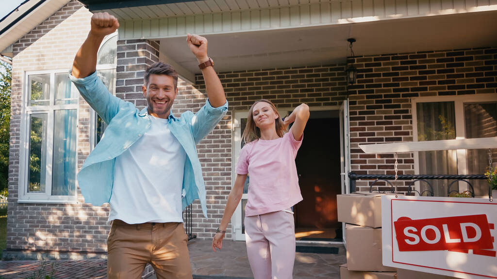взволнованный мужчина радуется рядом с женой, новый дом и продается питание  - Фото, изображение