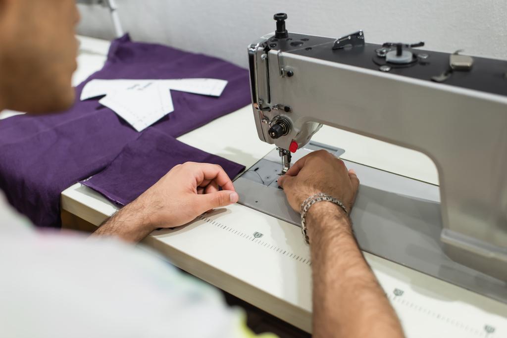 vista cortada de alfaiate borrado usando máquina de costura enquanto trabalhava no atelier - Foto, Imagem