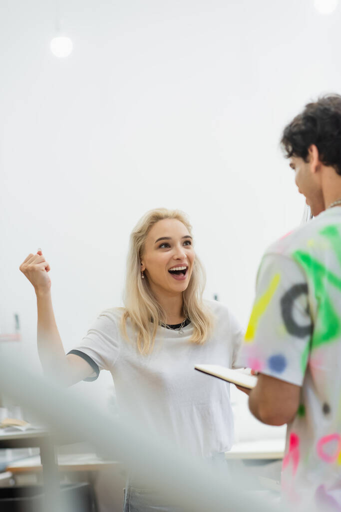 izgatott divattervező mutatja győzelem gesztus közel kolléga, elmosódott előtér - Fotó, kép