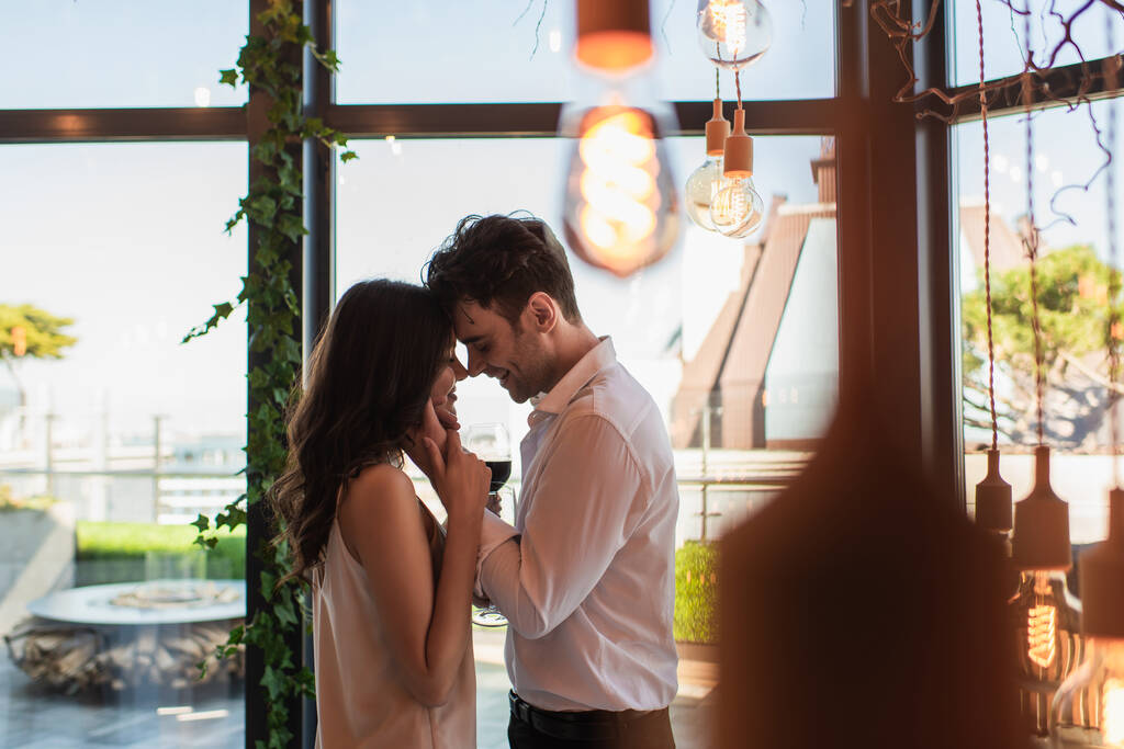 vue latérale de l'homme et de la femme souriant tout en s'embrassant dans le restaurant - Photo, image