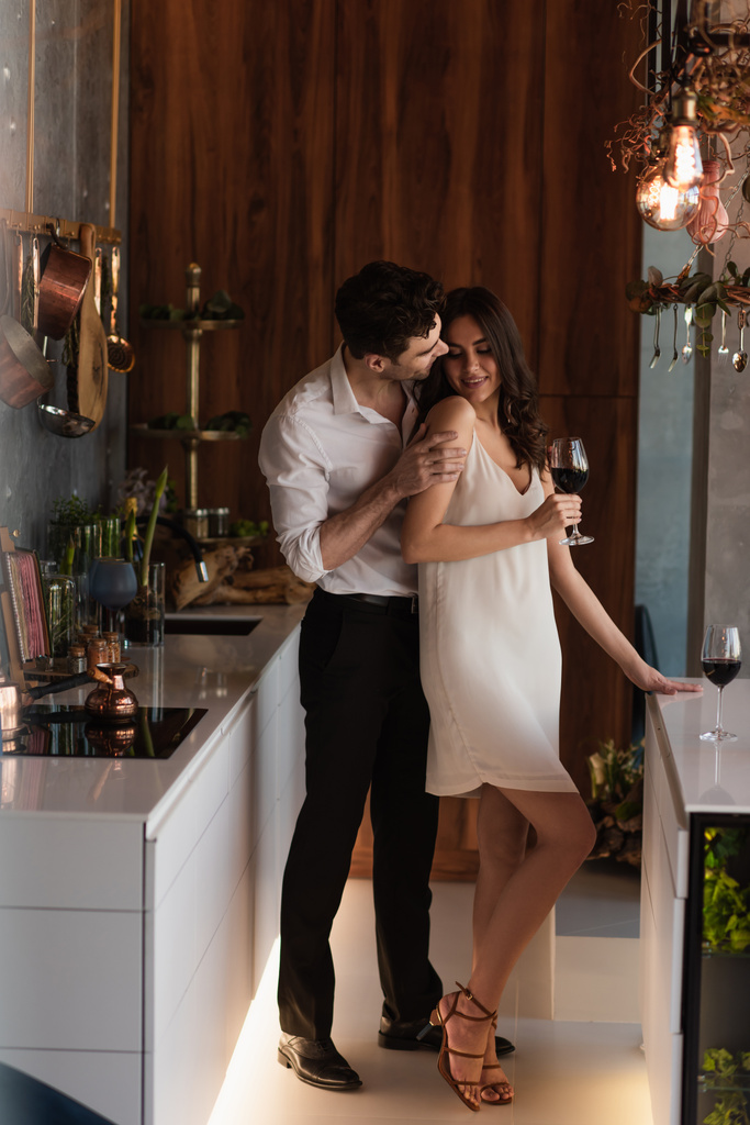 uomo sedurre sorridente fidanzata in abito antiscivolo con bicchiere di vino - Foto, immagini