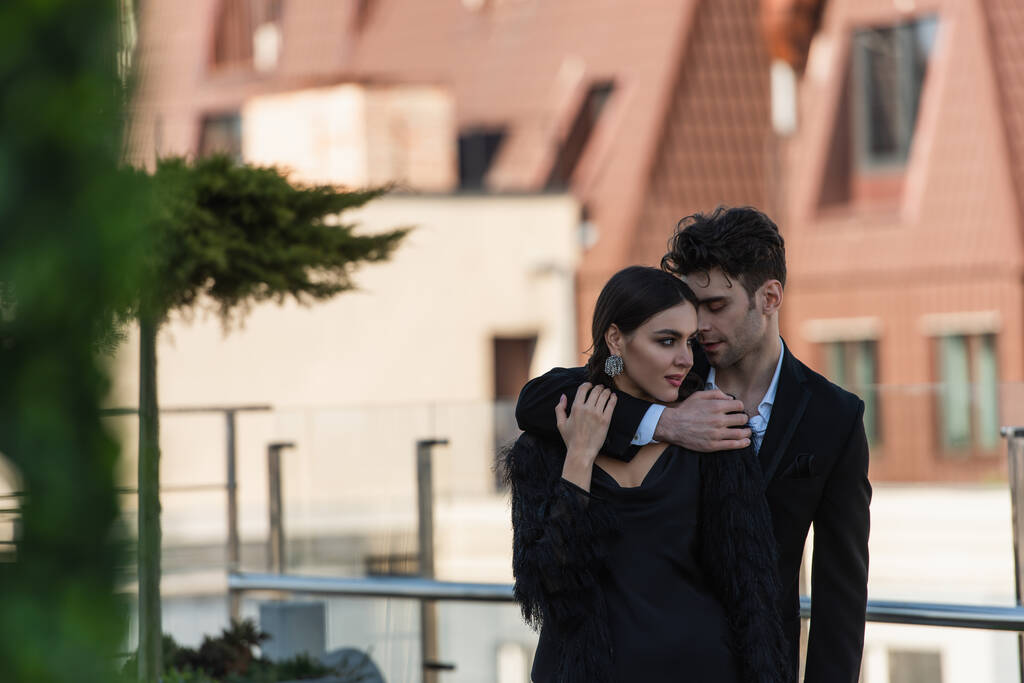 man hugging woman in black dress on terrace of restaurant  - Photo, Image