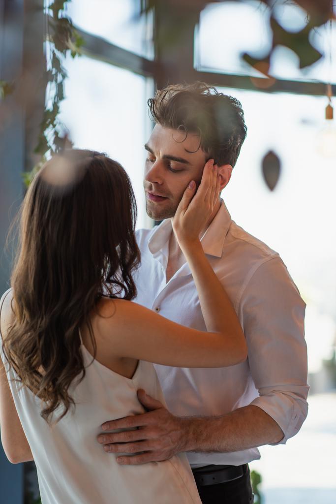 ブルネット女性でスリップドレスで男の顔に触れるレストラン  - 写真・画像