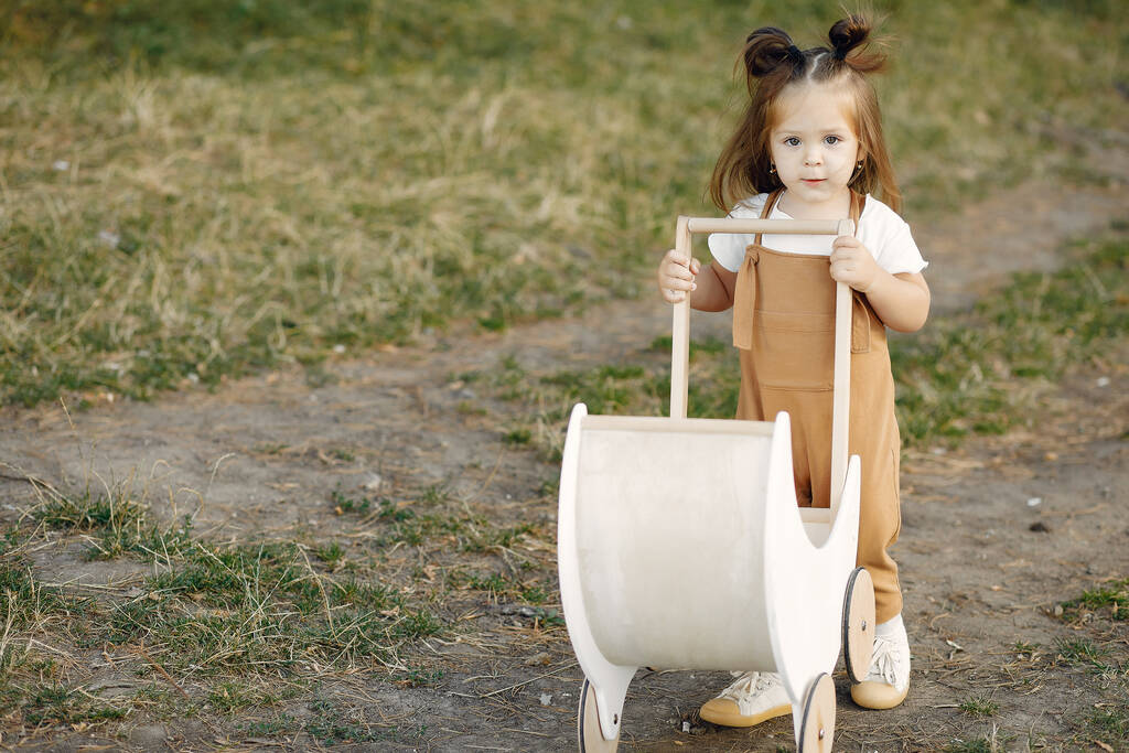 Милая маленькая девочка играет в парке с белой каретой - Фото, изображение