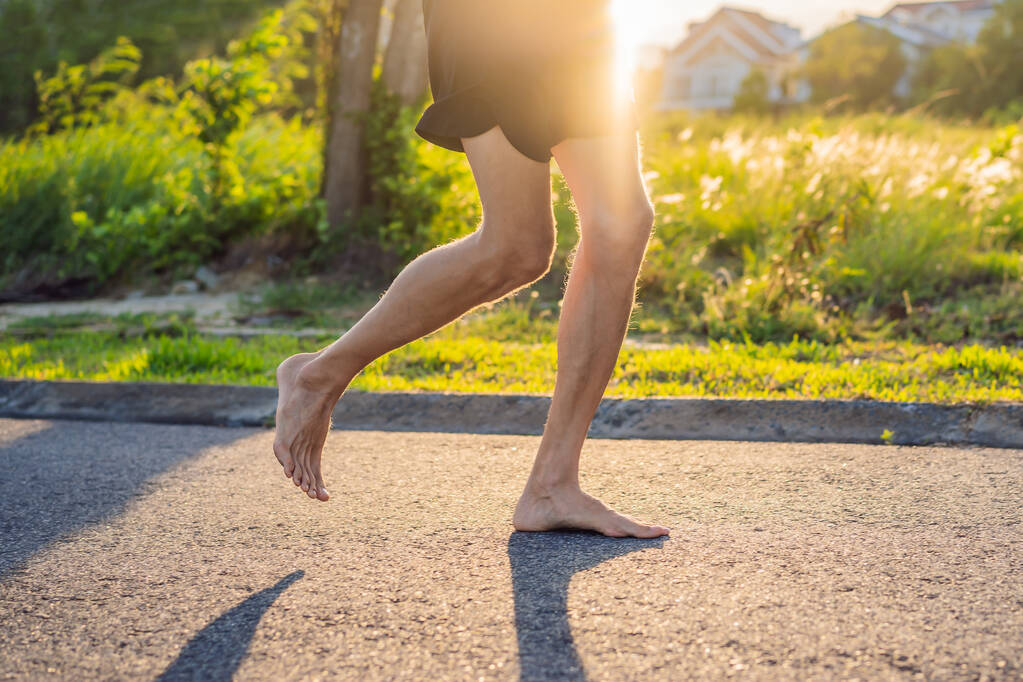 Ένας άνθρωπος δρομέας ασχολείται με το τρέξιμο στην άσφαλτο χωρίς παπούτσια, χωρίς αθλητικά παπούτσια, για την υγεία - Φωτογραφία, εικόνα