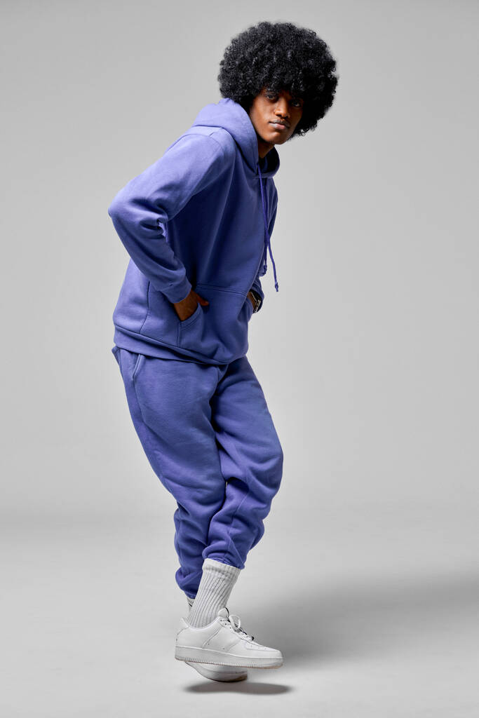 Joven hombre negro bailando en conjunto azul de chándal aislado sobre fondo gris - Foto, imagen