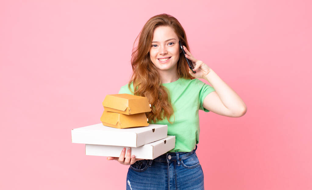 mooie rood hoofd vrouw holding weg te nemen fast food dozen - Foto, afbeelding