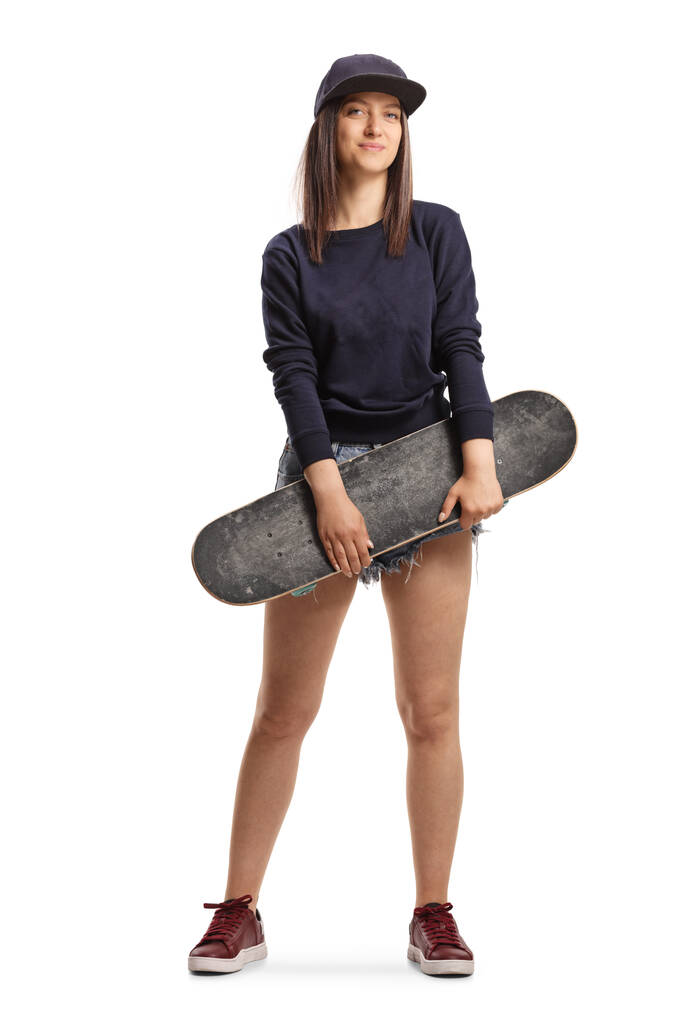 白地に隔離されたスケートボードを保持している女性スケーターの完全な長さの肖像画 - 写真・画像