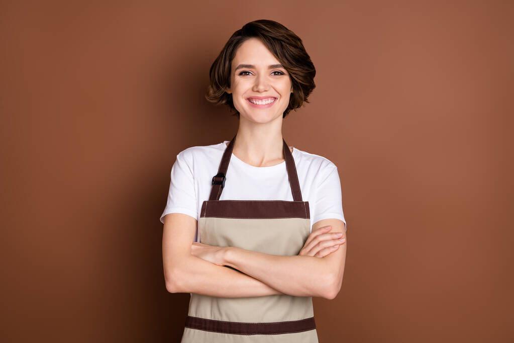 Muotokuva houkutteleva sisältö iloinen tyttö barista kahvila palvelu taitettu kädet eristetty yli ruskea väri tausta - Valokuva, kuva