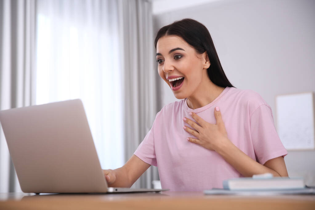 Mujer emocional participando en la subasta en línea utilizando el ordenador portátil en casa - Foto, imagen
